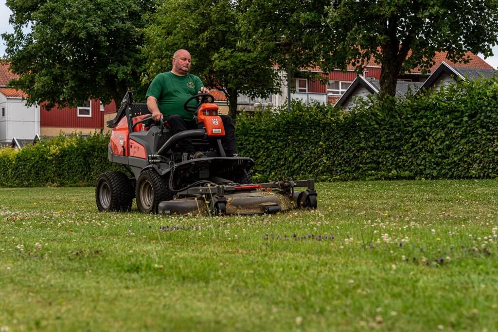 Ejendomsservice i hele Danmark. Her slår en af vores viceværter græs på et grønt område i Jylland.