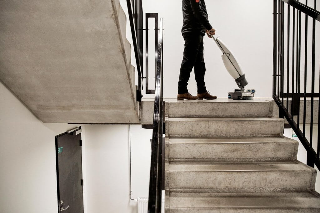 Billede af mand der vasker gulv på trapper med en gulvmaskine.