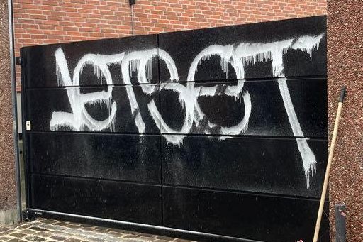 Billede af hvid graffiti på en sort port ved vision ejendomme i københavn